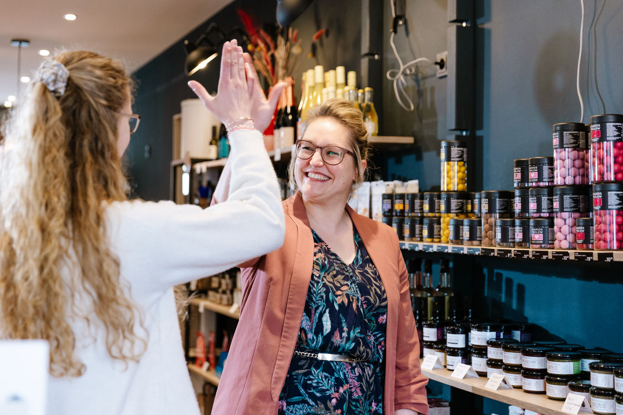 Zwei Kolleginnen geben sich lächelnd ein High five.