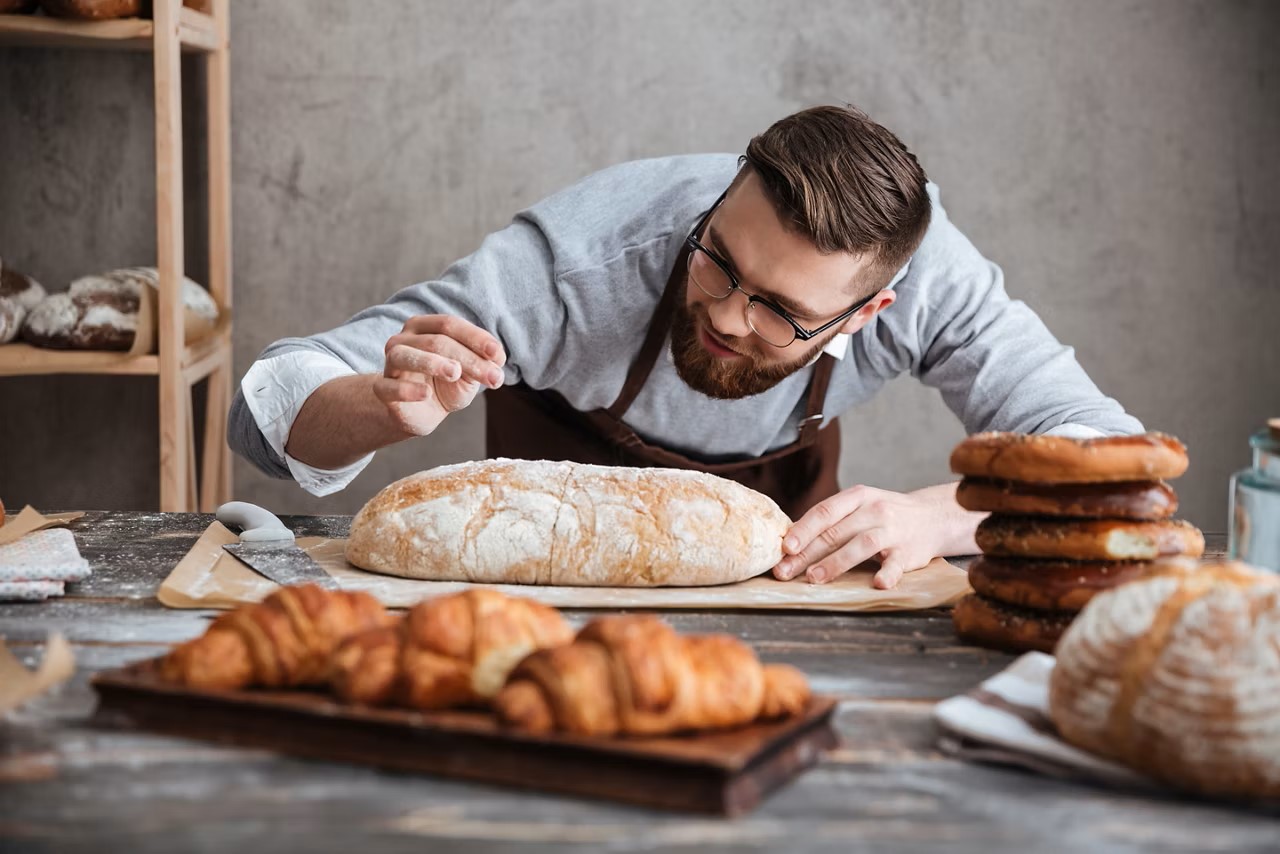 Eine junger Bäcker backt ein Brot.