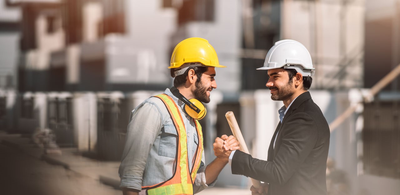 Junger Bauingenieur Manager und Architekten schütteln sich die Hände auf der Baustelle.
