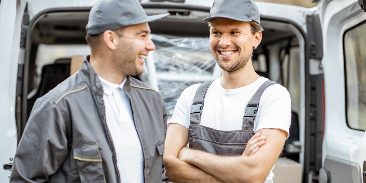 Porträt zweier Mitarbeiter eines Lieferunternehmens, die Waren mit dem Auto ausliefern.