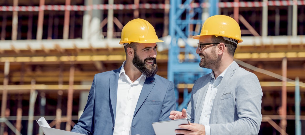 Zwei Geschäftsmänner besprechen Dokumente auf der Baustelle.