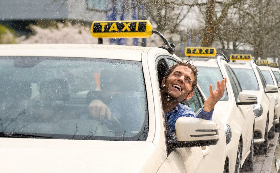 Eine Taxischlange und im vordersten Taxi schaut ein Taxifahrer aus dem Fahrerfenster.