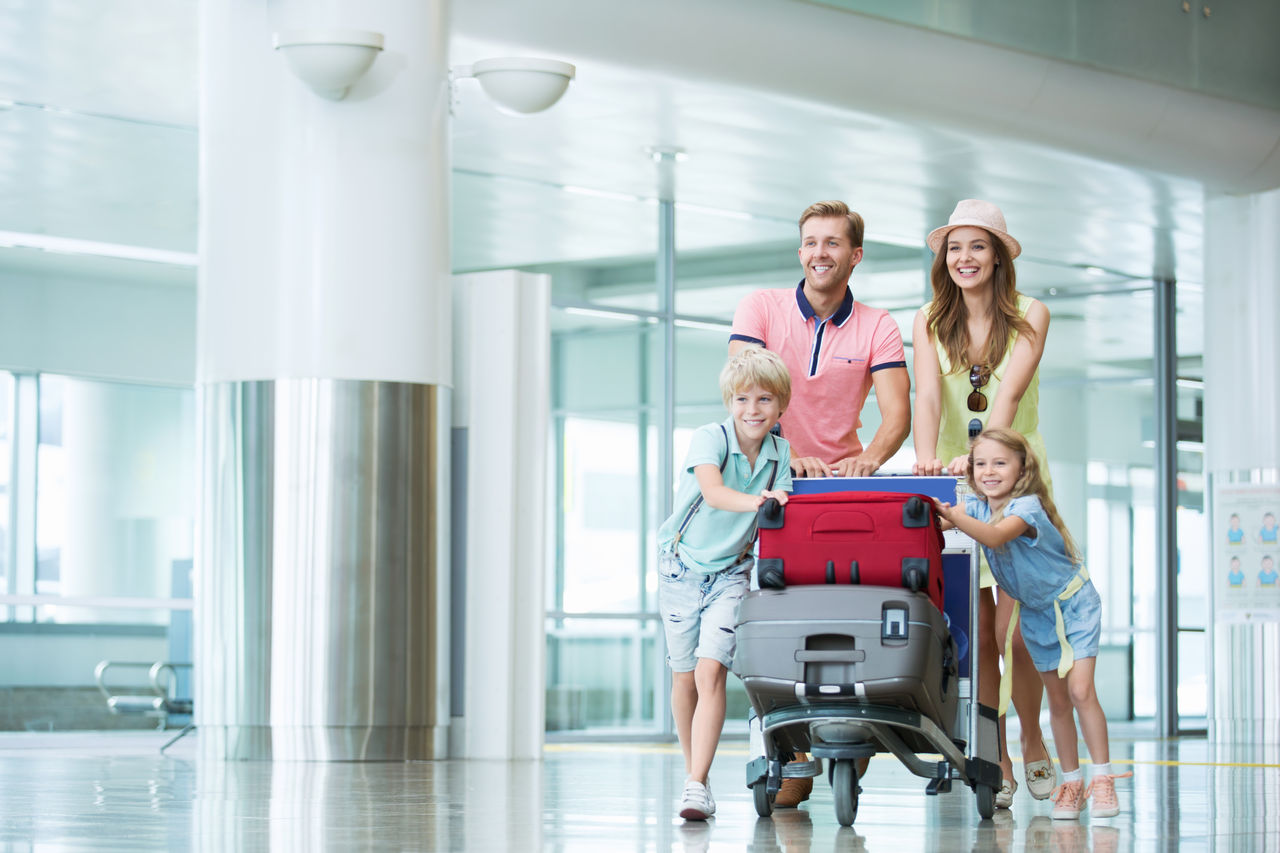 Eine Familie mit Koffern am Flughafen auf dem Weg zum Check-in.