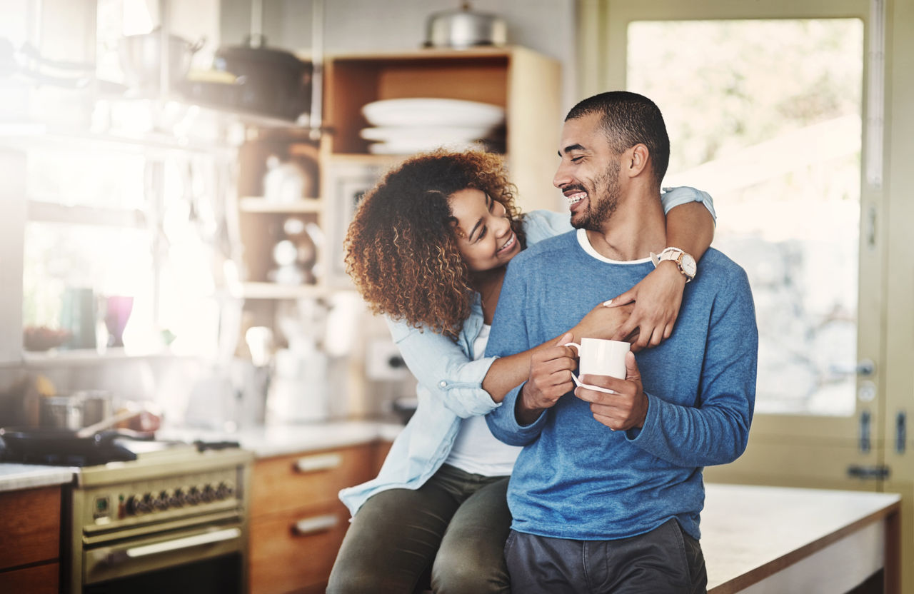 Liebe, Kaffee und glückliches Paar in der Küche, morgendliche Umarmung zu Hause mit Lächeln, Umarmung und gesunde Beziehung.